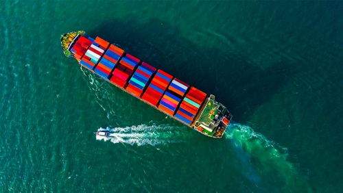Kleines Boot neben Containerschiff als Symbol für die Beiboot-Strategie